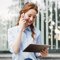 a woman looks at her tablet screen and talks on the phone